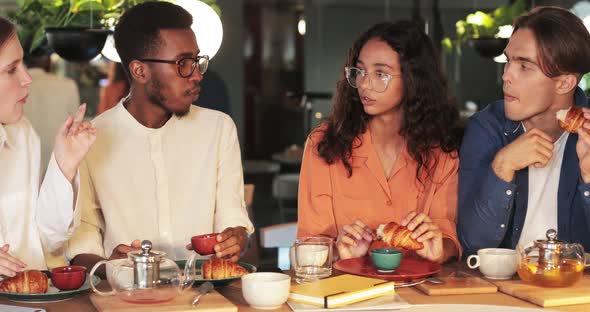 Young Woman Sharing Thoughts with Friends While They Spending Time in Cosy Cafe. Joyful Young Eating