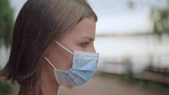 A Woman Moves Along the River Wearing a Mask