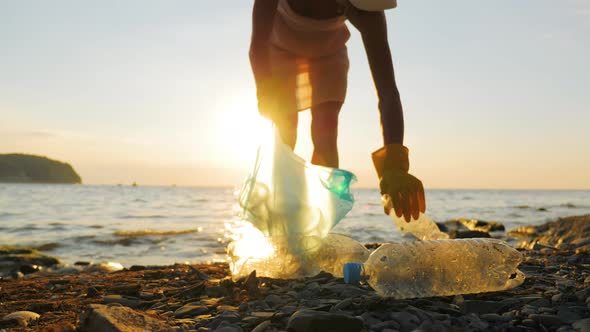 Hand Woman in Yellow Gloves Picking Up Empty Plastic Bottles Cleaning on the Beach