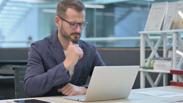 Middle Aged Businessman Thinking While Working on Laptop in Office