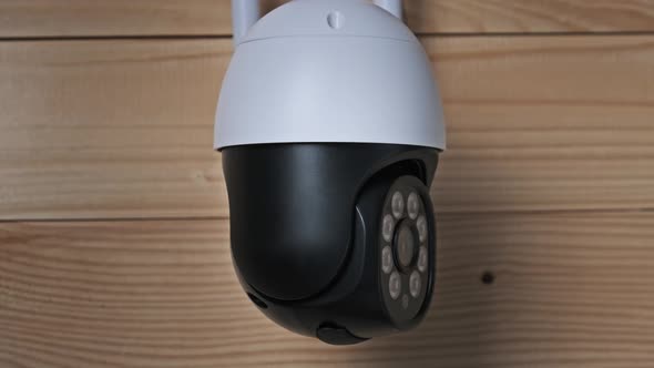 Security Camera Surveillance Rotates on Wooden Background