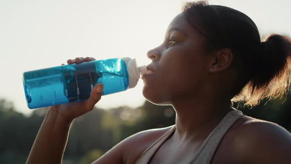 Woman drinking water during workout at park