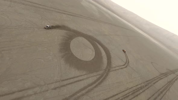 Aerial Rotation Shot Two Extreme Buggy Car Racing on Sandy Desert Surrounded By Dust and Smog