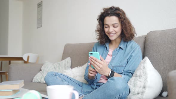 Hispanic Young Woman Using Smartphone App for Online Conference Sitting at Home