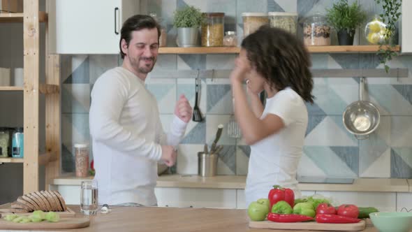 Happy Mixed Race Couple Dancing in Kitchen