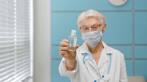 Skilled female doctor with glasses and protective mask stands in light hospital office
