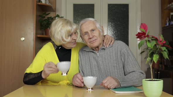 Happy Old Senior Couple Sit on Table at Home Enjoying Free Time Drink Tea