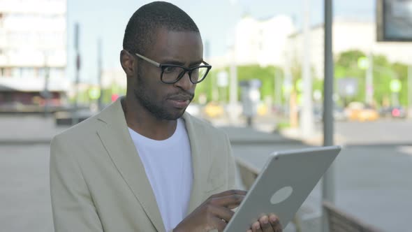 Upset African Man Reacting to Loss on Tablet Outdoor