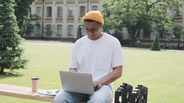 Stylish Male International Student Studying in the Campus on His Laptop