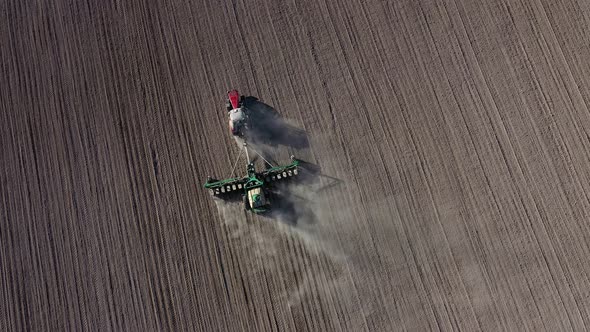 Aerial view of tractor with harrow system plowing ground on cultivated farm field