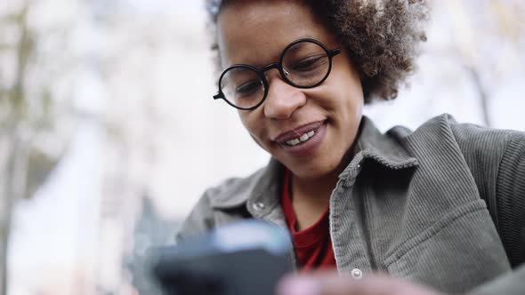 Handsome adult African woman wearing casual clothes typing by mobile