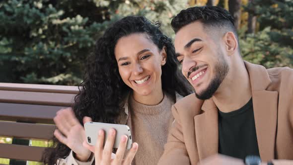 Positive Hispanic Couple Talking Online Chat Use Smartphone Guy and Girl Happily Smiling Waving