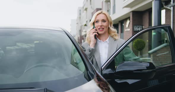 Businesswoman in Stylish Clothes Getting Out of Parked Vehicle and Talking on the Phone