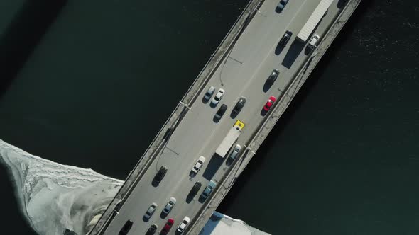 Car Traffic on the Bridge Against the Background of Snow and Water