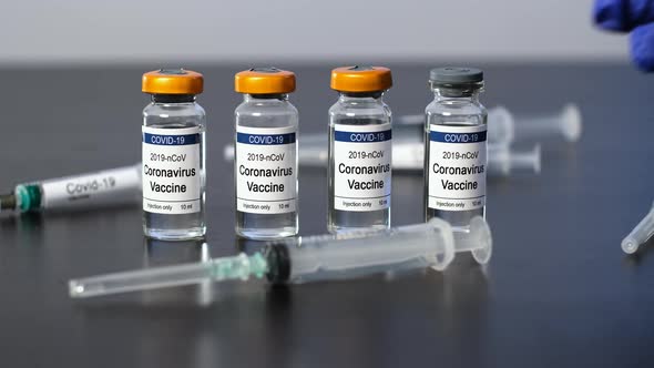 Hand Takes Syringe and Vial with COVID-19 Vaccine