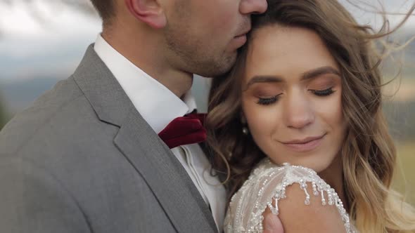 Lovely Young Newlyweds Bride and Groom Embracing Hugging on Mountain Slope Wedding Couple in Love