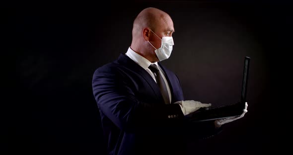 Portrait of a Man in a Business Suit, a Disposable Mask and White Protective Gloves on a Black