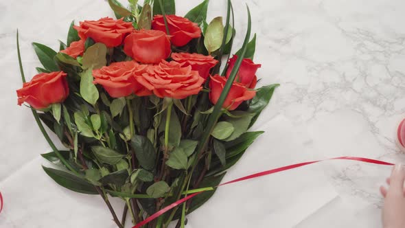 Flat lay. Florist wrapping red roses into a beautiful bouquet