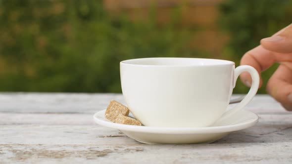 Hand putting cup of tea on the table