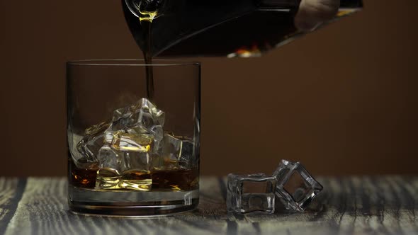 Pouring Whiskey, Cognac Into Glass. Dark Background. Pour of Alcohol Drink