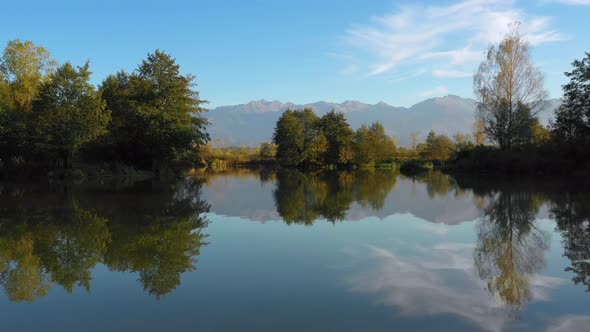 Lake at the edge of the mountains with forest reflected in the clear water. Idylic autumn landscape