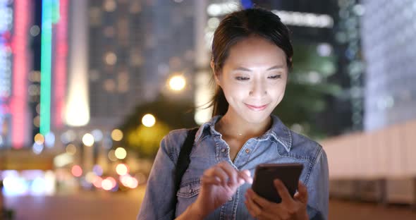 Woman use of mobile phone in Hong Kong city at night 