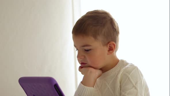 Happy little boy watching cartoon on digital tablet at home