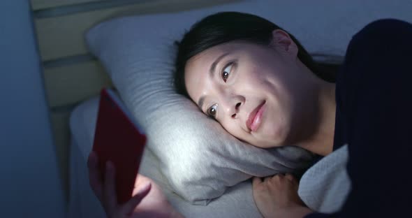 Woman Watch on Mobile Phone and Lying on Bed at Night