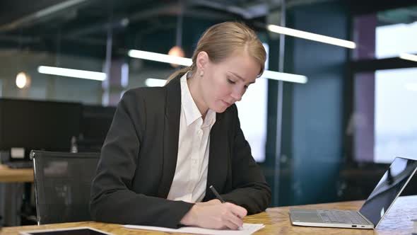 Young Businesswoman Trying To Write on Documents in Office