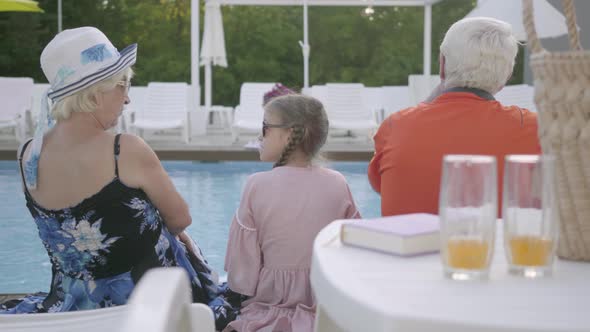 Happy Family Sitting on the Edge of the Pool, Back View