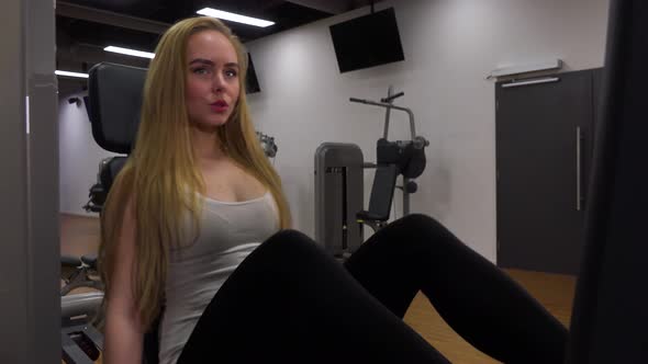 A Young Beautiful Woman Trains on a Leg Press Machine in a Gym - Closeup