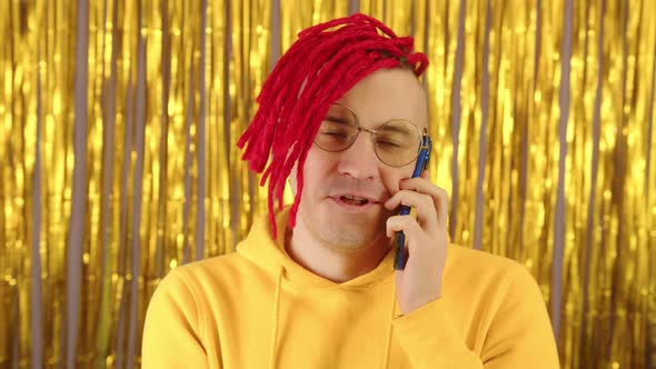 Young Man with Red Dreadlocks Speaks on Smartphone