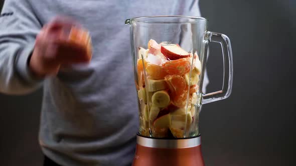 A man makes a nutritious fresh homemade fruit cocktail on an electric blender.