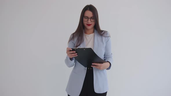 Confident Young Business Lady Stands Against an Isolated White Background and Holds a Clipboard in