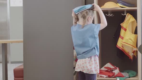 Little girl playing dress up game in kids section of public library.