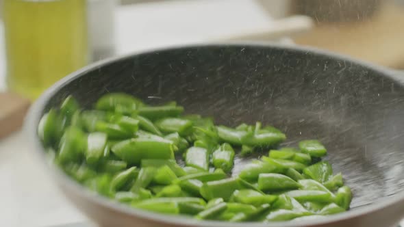 Unrecognizable cook frying green beans in pan