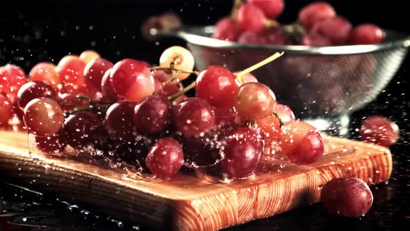 Grapes Fall on a Cutting Board with Splashes of Water