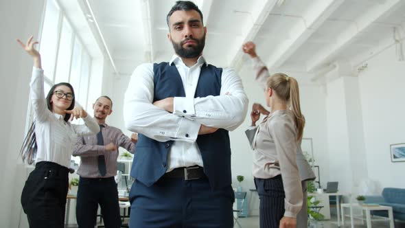 Low Angle View of Serious Business Owner Standing at Corporate Event While People Dancing