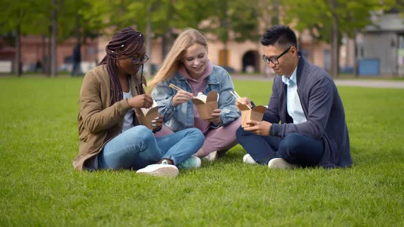 Multiethnic Students Talking and Eating Takeaway Meal Relaxing in Summer Park