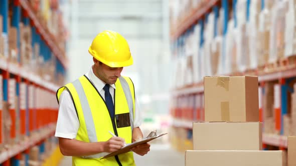 Male warehouse worker writing on clipboard