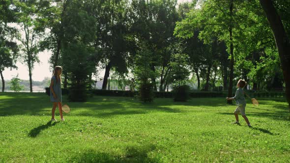 Two Joyful Siblings Playing Badminton on Sunny Summer Day