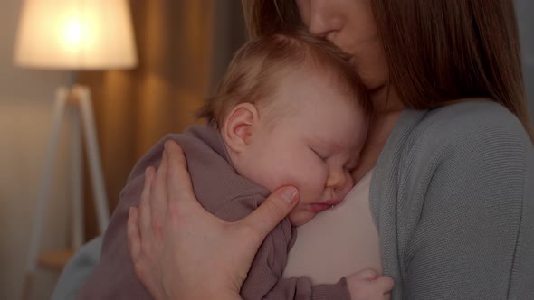 Loving Mother Kissing Adorable Newborn Baby Sleeping On Her Chest