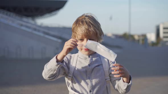 Caucasian Schoolboy Putting on Face Mask