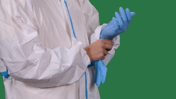 Male Medical Worker Professional in a White Protective Suit Puts on Blue Surgical Gloves