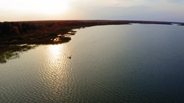 Aerial Footage of a Boat Sailing in a Lake at Sunset in Autumn