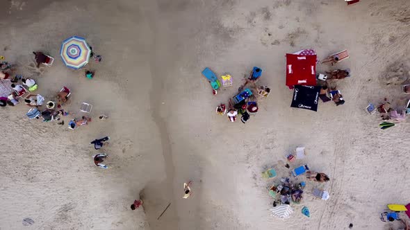 Aerial top down shot of people enjoying on a crowded beach in Brazil. Dolly right