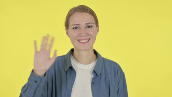 Young Woman Waving Welcoming on Yellow Background