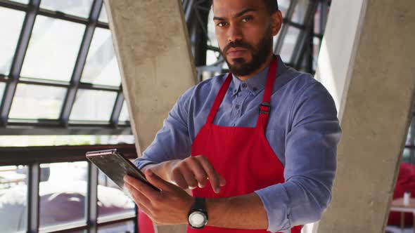 Portrait of mixed race male cafe owner using tablet and looking to camera