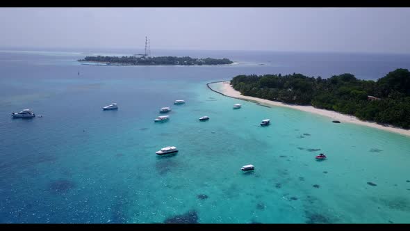 Aerial drone scenery of tranquil resort beach lifestyle by aqua blue ocean with white sandy backgrou