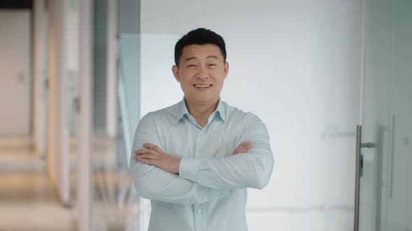 Successful Middle Aged Asian Businessman Posing at Office Building Crossing Hands and Smiling to